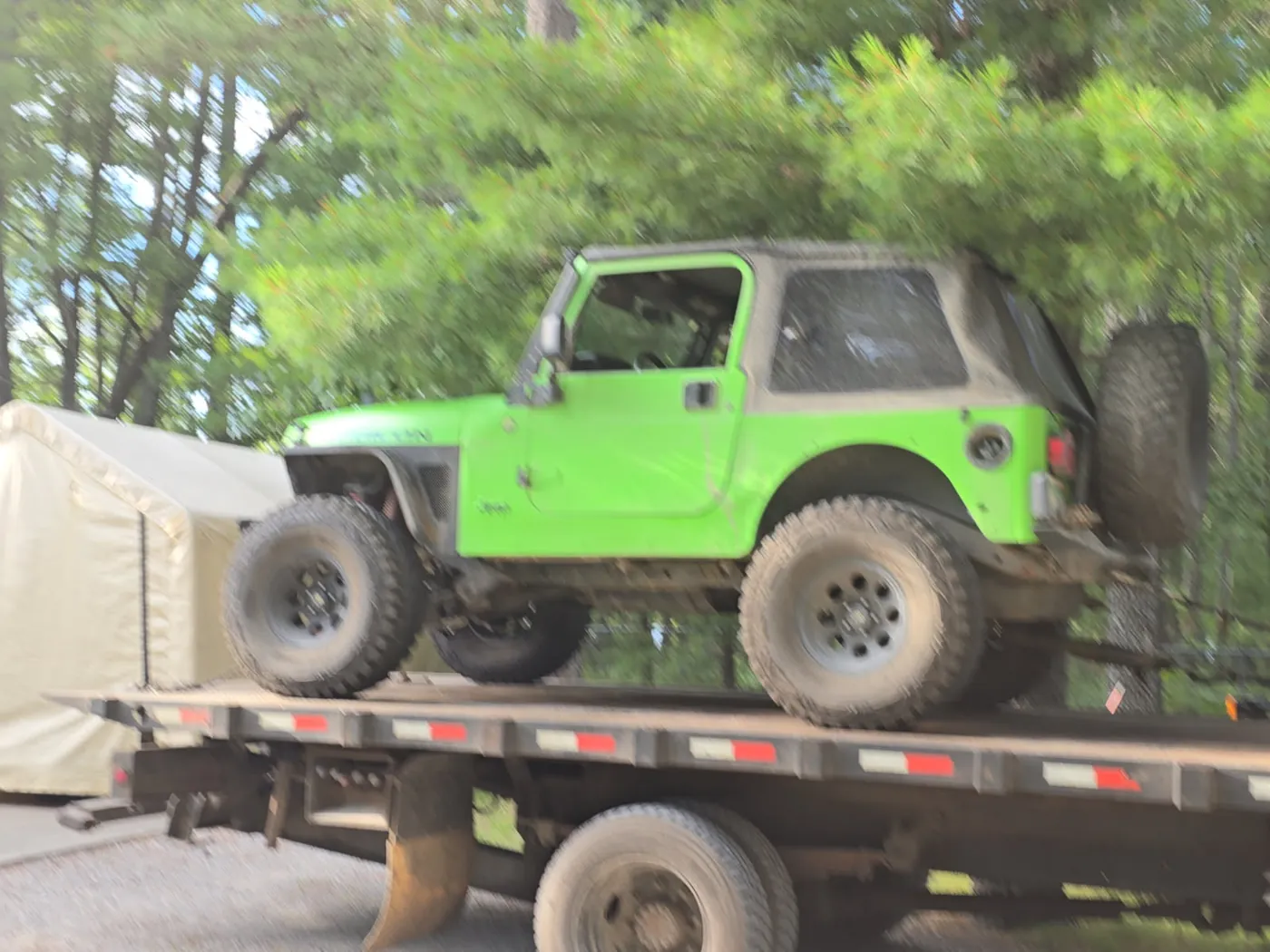 Lifted lime-green Jeep Wrangler loaded on a C&C Inc flatbed tow truck in Northern Michigan