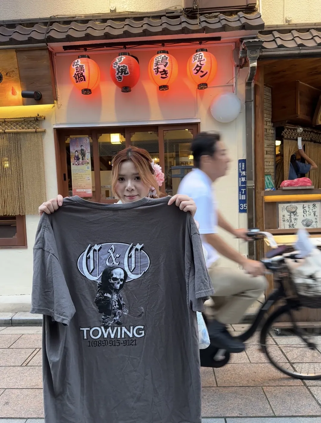 Holding up a C&C Towing skull logo t-shirt outside a restaurant in Asakusa, Tokyo, Japan