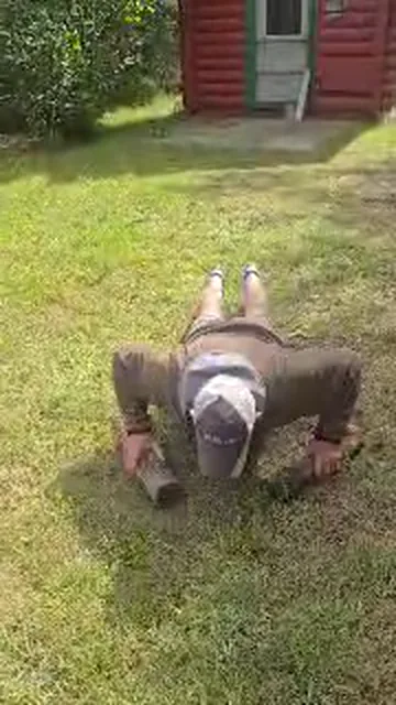 Customer doing 20 push-ups on a backyard lawn by a log cabin to earn $20 off a C&C Inc tow in Northern Michigan